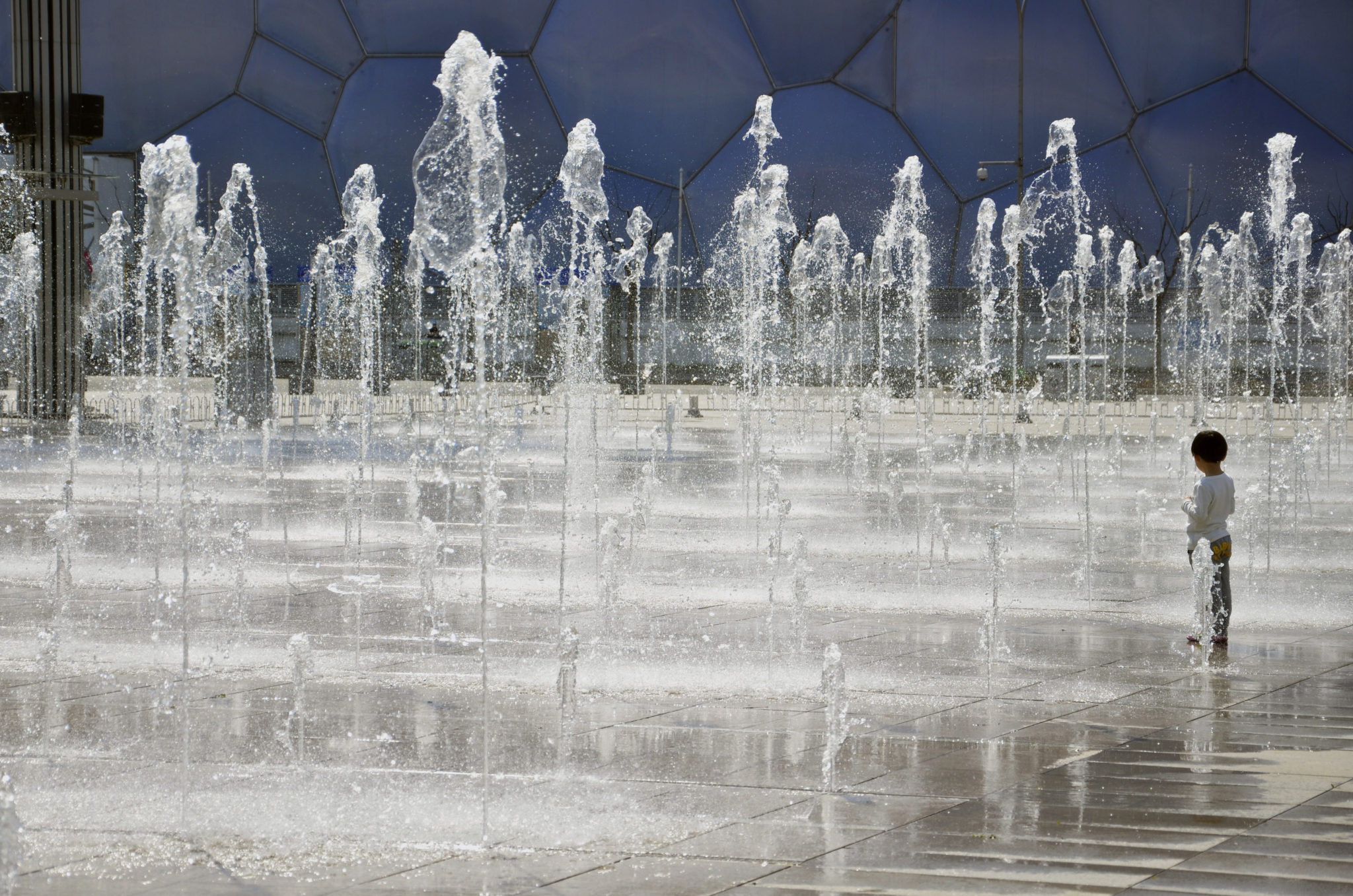 Ein Kind spielt im Springbrunnen im Olympiapark