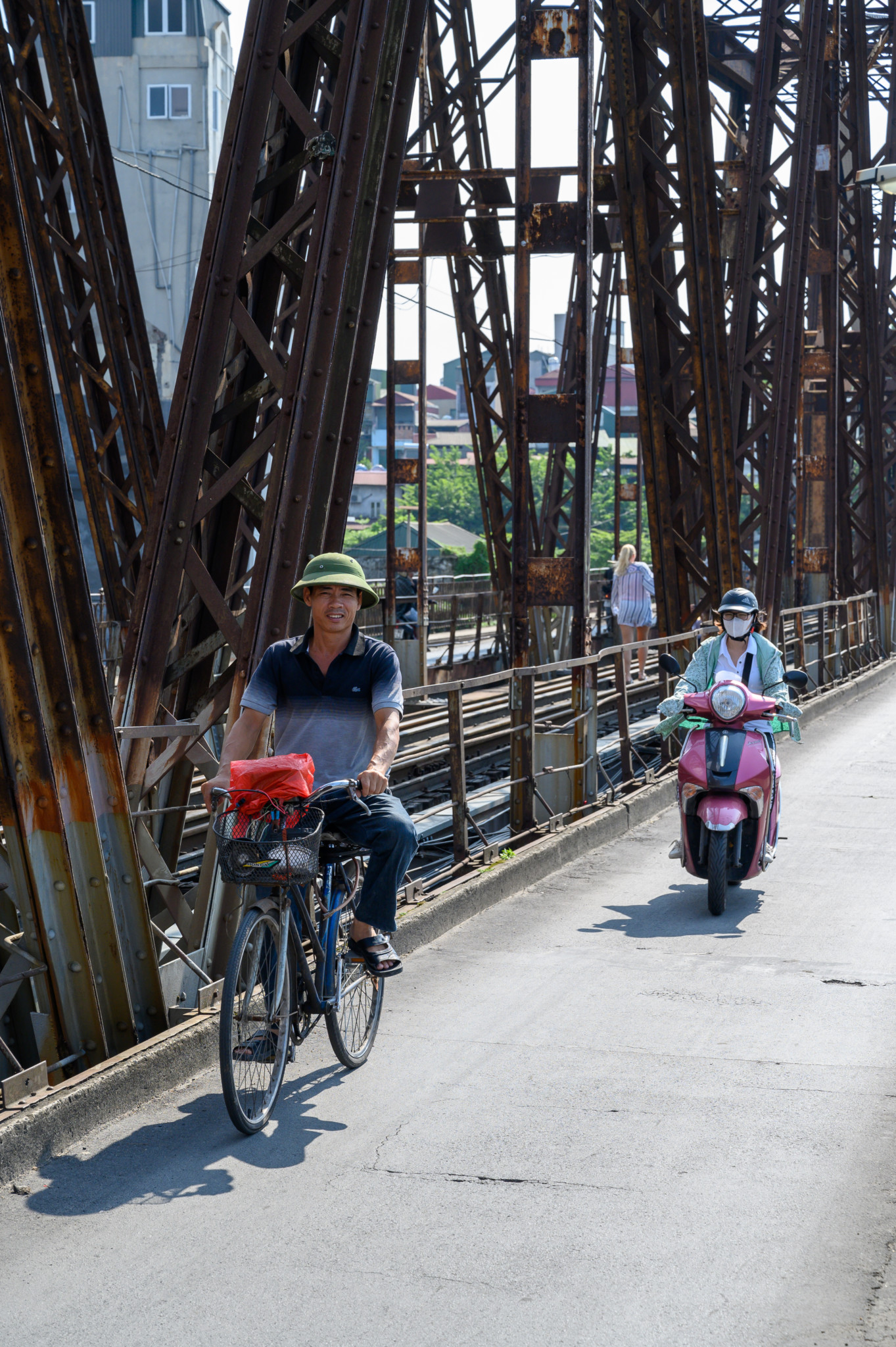 Fahrradfahrer und Rollerfahrer auf der Long Bien Brücke in Vietnam