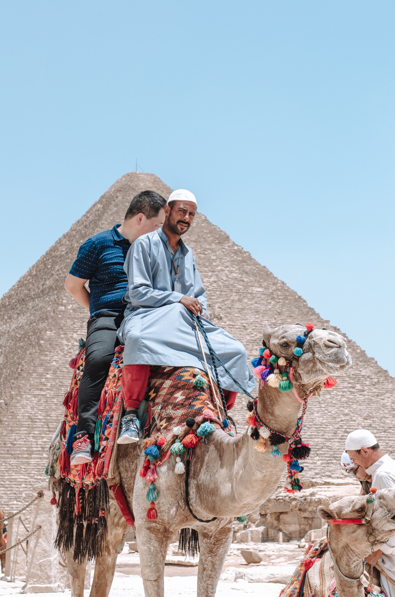 Ein Kamelführer mit einem Touristen beim Kamelreiten